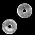 zwei helle halbtransparente Selenit Donuts auf dunklem Grund