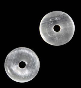 zwei helle halbtransparente Selenit Donuts auf dunklem Grund